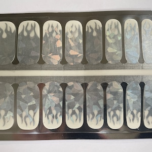 May include: A sheet of nail polish wraps with a holographic finish and a flame design. The wraps are packaged in a clear plastic sleeve.