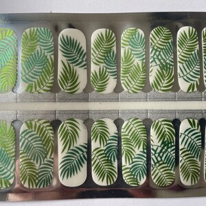 Puede incluir: Tiras de arte de u&ntilde;as con un dise&ntilde;o de hojas tropicales. Las tiras de u&ntilde;as presentan un patr&oacute;n repetido de hojas de palma verdes sobre un fondo blanco. Las tiras de u&ntilde;as est&aacute;n en un paquete plateado.