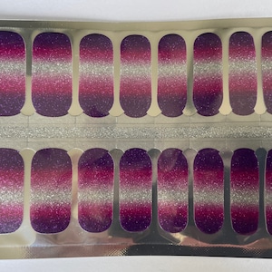 Peut inclure: Une feuille d'autocollants pour ongles avec un design dégradé. Les autocollants présentent un design de paillettes violettes, roses et argentées.