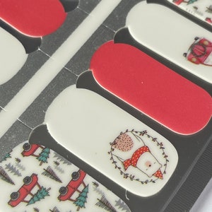 May include: A sheet of nail polish strips featuring a festive Christmas theme. Designs include red and white patterns, a polar bear wearing a scarf, and red trucks carrying Christmas trees. The strips are in various sizes.