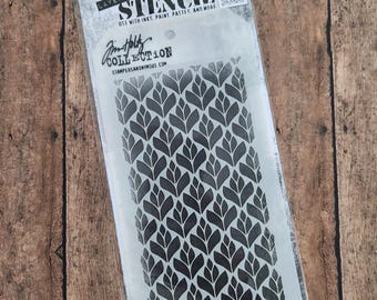 Op de afbeelding: Een zwart-witte stencil met een herhalend patroon van gestileerde bladeren. De stencil is verpakt in een doorzichtige plastic zak met een wit label waarop "Stampers Anonymous Collection Stencil" staat.