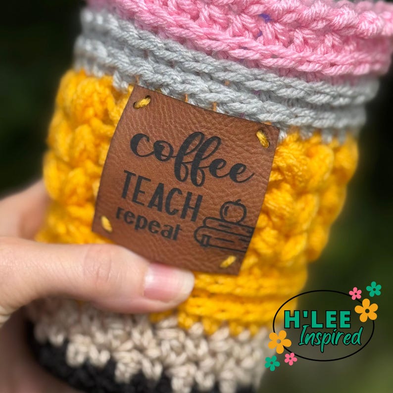 May include: A crocheted coffee cup cozy in the shape of a pencil with a brown leather patch that says "coffee teach repeat".
