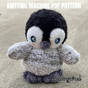 Könnte beinhalten: Ein graues und schwarzes Plüschpinguin-Spielzeug mit blauen Augen. Der Pinguin ist aus einem flauschigen Stoff gefertigt und hat einen kleinen schwarzen Schnabel. Das Spielzeug sitzt auf einer grauen Oberfläche. Der Text "@hleeinspired" ist in der unteren rechten Ecke des Bildes sichtbar.