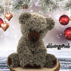 Op de afbeelding: Een pluche bruine teddybeer met een donzige textuur zit op een houten oppervlak. De beer heeft zwarte ogen en een bruine neus. De beer is omringd door kerstversiering, waaronder rode en gouden ornamenten.
