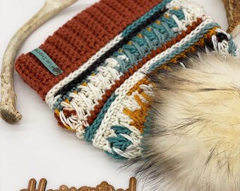 Peut inclure: Un chapeau crocheté avec un motif géométrique coloré et un pompon en fausse fourrure. Le chapeau a une étiquette en cuir marron avec le texte "Hilla Threads" dessus. Le chapeau est posé sur une surface en bois avec une pancarte en bois qui dit "@hleeinspired".