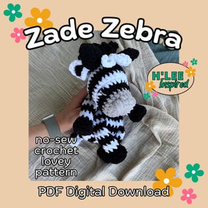 Könnte beinhalten: Ein gehäkeltes Zebra-Spielzeug in Schwarz-Weiß-Streifen, mit einer grauen Schnauze und schwarzen Hufen. Der Text "Zade Zebra" wird über dem Zebra angezeigt. Das Bild enthält auch den Text "no-sew crochet lovey pattern" und "PDF Digital Download".