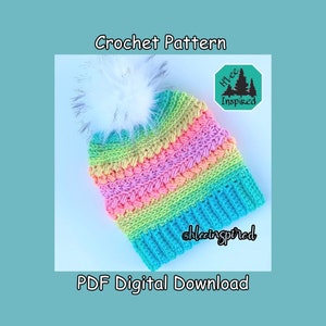 Op de afbeelding: Een haakpatroon voor een kleurrijke regenboogmuts met een witte pompon. Het patroon is een digitale PDF-download en bevat de tekst "Hive Inspired".