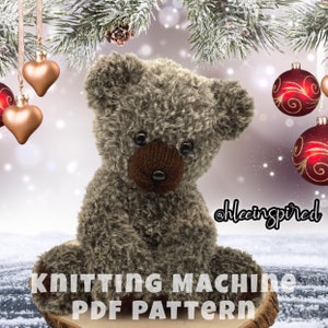 Op de afbeelding: Breipatroon voor een bruine teddybeer met zwarte ogen en een bruine neus. Het patroon is beschikbaar als PDF-download. De afbeelding toont de teddybeer zittend op een houten basis met een besneeuwde achtergrond en kerstversiering.