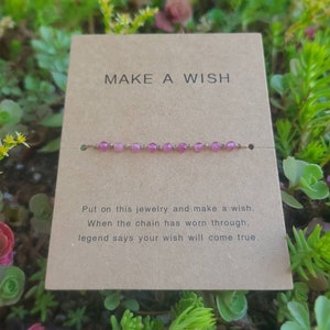 May include: A pink beaded bracelet with a gold chain. The card reads "MAKE A WISH" and says "Put on this jewelry and make a wish. When the chain has worn through, legend says your wish will come true."
