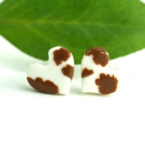 May include: A pair of brown and white heart-shaped earrings with a cow print pattern.
