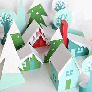 May include: A whimsical paper village scene featuring houses, trees, and mountains in shades of green, blue, red, and white. The houses have white roofs and green doors. The trees are various shapes and sizes, creating a charming, miniature landscape.