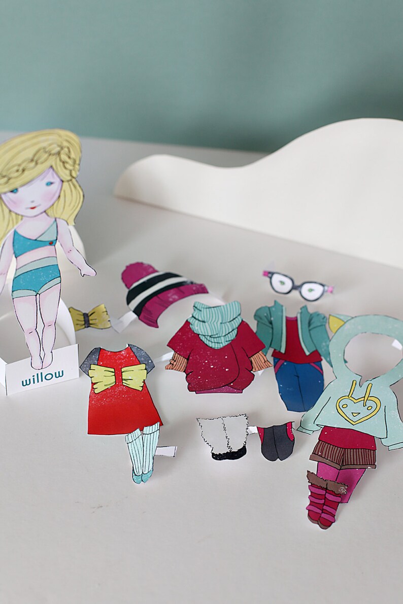 May include: A paper doll named Willow with various outfits and accessories. The outfits include a red dress, a red sweater with a scarf, a blue jacket, and a light blue hoodie. Accessories include a bow, glasses, a hat, and boots.