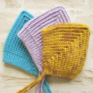 May include: Three crocheted baby bonnets in different colors: light blue, lavender, and yellow.