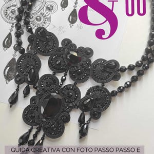 May include: A black soutache necklace with a large central pendant and dangling teardrop-shaped beads. The necklace is displayed on a white surface with sketches and text in Italian. The text includes "Soutache & Co" and "Guida Creativa".