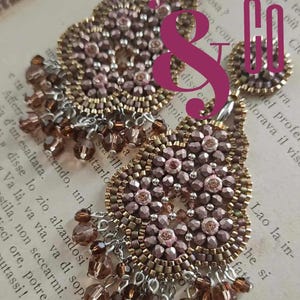 May include: Close-up of handcrafted beaded earrings in shades of brown, gold, and pink. The earrings feature intricate floral patterns and dangling beads. The design is set against a backdrop of printed text.
