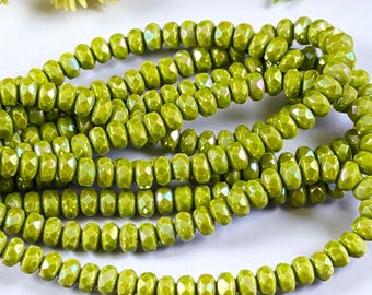 May include: A collection of lime green faceted rondelle beads arranged in multiple loose strands. Each bead features a shiny, reflective surface with a subtle iridescent finish, creating a uniform appearance across the entire group of beads.