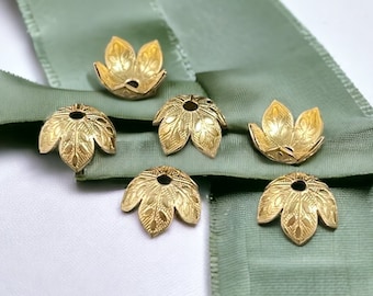 May include: Six gold-toned metal bead caps, each shaped like a five-petaled flower with a central hole. The surface of each cap features an embossed leaf-like texture with fine lines and small oval details, creating a decorative finish.