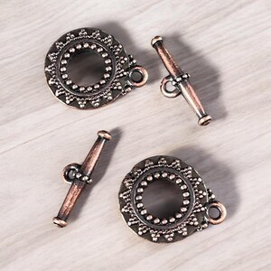 May include: Two antique copper-toned toggle clasps with ornate circular designs and two matching straight toggle bars.
