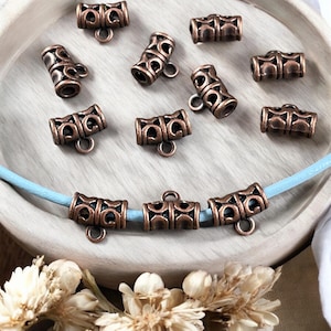 May include: A collection of 10 antique copper-toned metal end caps for jewellery making. The end caps have a decorative, ornate design and a loop for attaching to a cord or chain.