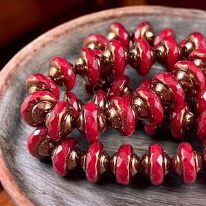 May include: A strand of red and gold glass beads. The beads are faceted and have a spiral design.