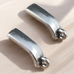 May include: Two silver-toned metal charms in the shape of a curved bar with a loop at the end.