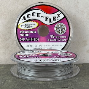 May include: A spool of silver Accu-Flex beading wire with 49 strands. The label reads "Professional Quality Beading Wire Classic 30 ft. (9.1 m) .019 in. (.48 mm) dia. Made in Reorder E23-1549BS".