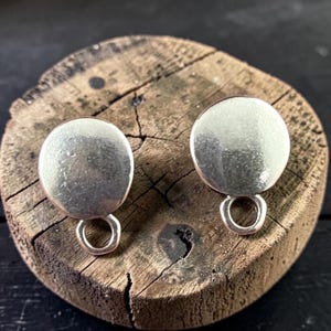 May include: A pair of circular silver-toned metal earring components, each featuring a smooth, flat, round disc top attached to a small, open circular loop at the bottom, designed for jewelry making and assembly of dangling earrings.