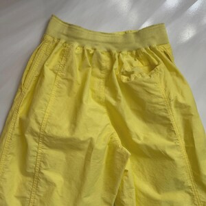 Puede incluir: Pantalones cortos deportivos de color amarillo brillante con una cintura ancha y acanalada y bolsillos laterales. Los pantalones cortos est&aacute;n hechos de una tela ligera y presentan costuras visibles.