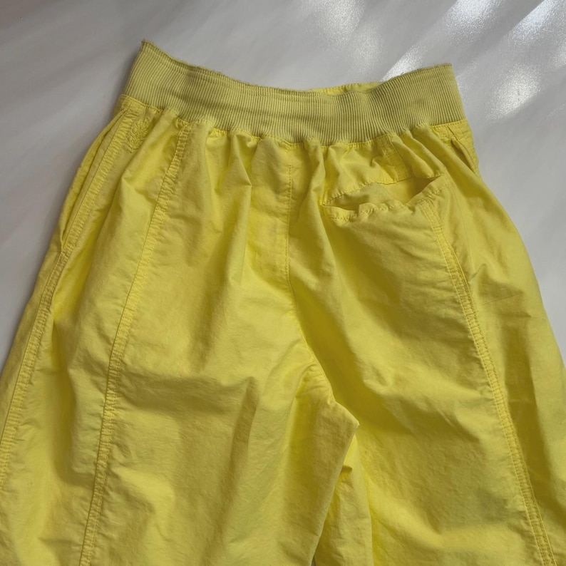 Puede incluir: Pantalones cortos deportivos de color amarillo brillante con una cintura ancha y acanalada y bolsillos laterales. Los pantalones cortos est&aacute;n hechos de una tela ligera y presentan costuras visibles.