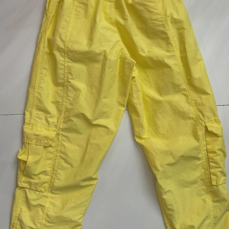 Puede incluir: Pantalones cargo de color amarillo brillante con m&uacute;ltiples bolsillos y cintura con cord&oacute;n. Los pantalones est&aacute;n hechos de un material ligero y tienen detalles de costura visibles. El estilo casual es adecuado para el uso diario.