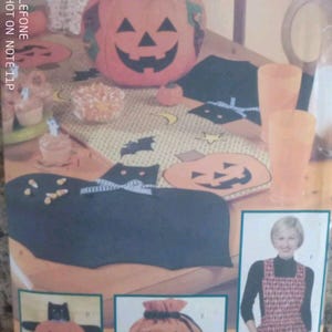 Peut inclure: Un patron de couture pour des articles en tissu sur le thème d'Halloween, incluant une peluche citrouille, un set de table chat noir, un chemin de table citrouille, un sac à cordon et un tablier à carreaux. La pochette montre les projets finis.