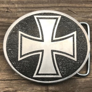Könnte beinhalten: Eine silberne Gürtelschnalle mit schwarzem Hintergrund und einem weißen Eisernen Kreuz.