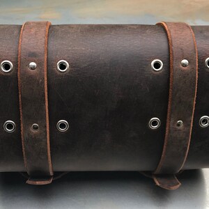 May include: A brown leather motorcycle saddlebag with metal buckles and eyelets.