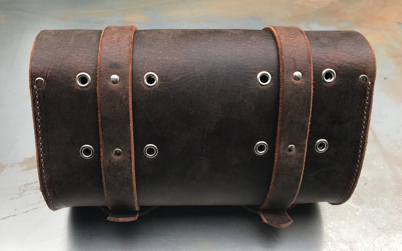 May include: A brown leather motorcycle saddlebag with metal buckles and eyelets.