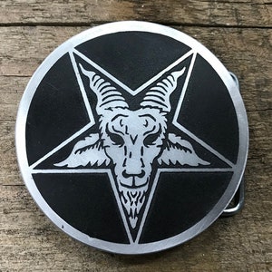 May include: A silver belt buckle with a black background and a silver pentagram with a goat's head inside.