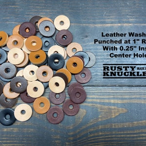 May include: A pile of leather washers in various shades of brown, black, and gray. The washers are 1 inch in diameter with a 0.25 inch inset center hole. The text "Leather Washers Punched at 1" Round With 0.25" Inset Center Hole" and "RUSTY KNUCKLES MADE IN USA" is visible in the image.