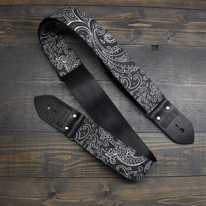 May include: Black and white paisley guitar strap with leather ends. The strap is made of a soft, comfortable material and is adjustable.