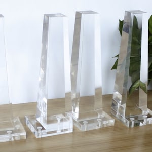 May include: Four clear acrylic table legs with a square base. The legs are angled and have a modern design.