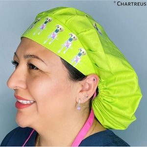 May include: A bright green surgical scrub hat with a pattern of brown and white dogs wearing pink collars. The hat has a gathered back and a tie at the back.