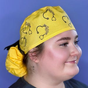 May include: A yellow surgical scrub hat with a black floral design and a stethoscope pattern.