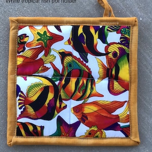 May include: White pot holder with a tropical fish design. The pot holder has a yellow border and a white background with colorful fish and starfish.