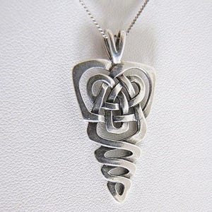 May include: A silver pendant necklace featuring a Celtic knot design. The pendant has an intricate, interwoven pattern and a teardrop shape. The necklace chain is a delicate silver colour.