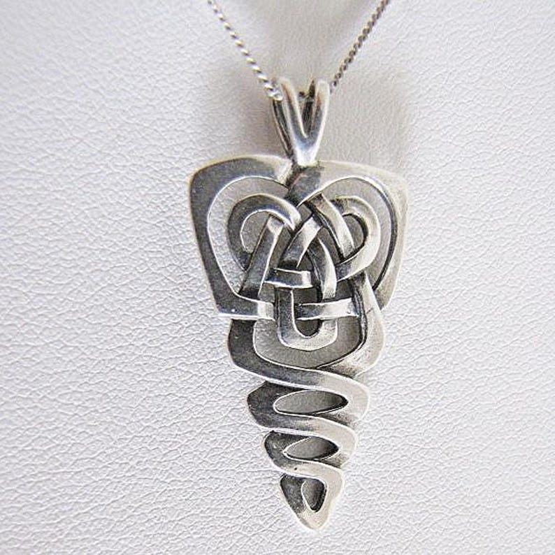 May include: A silver pendant necklace featuring a Celtic knot design. The pendant has an intricate, interwoven pattern and a teardrop shape. The necklace chain is a delicate silver colour.