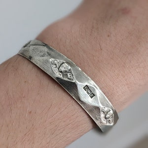 May include: A silver bracelet with a textured surface and a hallmark that reads "925".