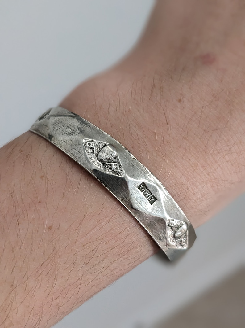 May include: A silver bracelet with a textured surface and a hallmark that reads "925".
