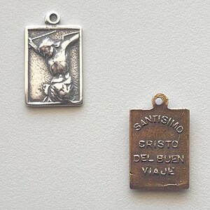 May include: Silver pendant with a depiction of Jesus Christ on the cross on one side and the words "SANTISIMO CRISTO DEL BUEN VIAJE" on the other side.