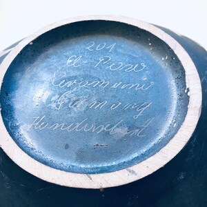 May include: A blue ceramic vase with a white rim and a handwritten inscription on the bottom that reads "201 el Porro ceram uni 6.5 cm my Hundeblatt".