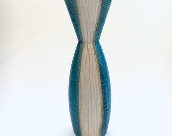 May include: A white ceramic vase with blue and yellow stripes. The vase has a narrow neck and a wide base.