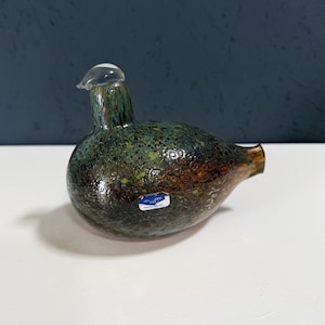 May include: A decorative glass bird figurine with a speckled green, brown, and clear design. The bird has a rounded body, a small head, and a clear glass beak. The figurine is a unique piece of home decor.