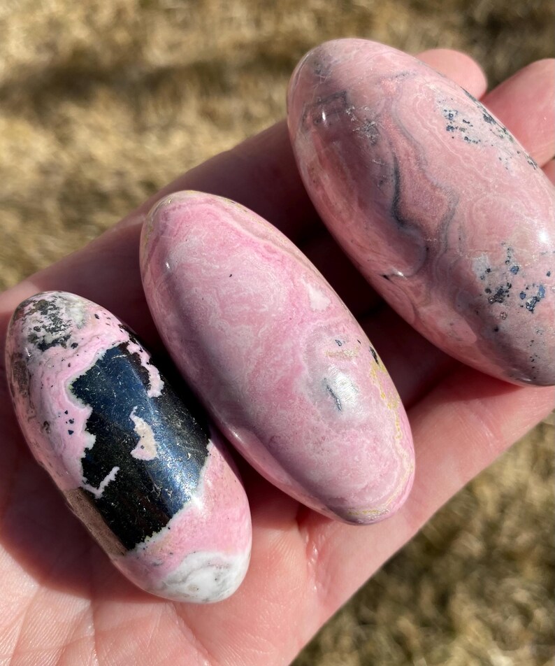 Pu&ograve; includere: Tre pietre levigate di colore rosa e nero con una forma ovale liscia. Le pietre presentano un motivo a spirale di rosa e nero.
